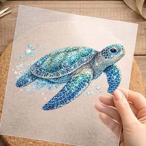 Könnte beinhalten: Ein quadratisches, transparentes Blatt mit einer detaillierten Illustration einer Meeresschildkröte. Die Schildkröte ist in Blau-, Türkis- und Grüntönen gehalten und weist eine funkelnde, glitzernde Textur auf. Kleine Blasen umgeben die Schildkröte.
