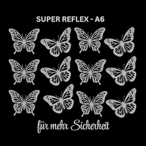 Könnte beinhalten: Ein Bogen mit silberfarbenen reflektierenden Schmetterlingsaufklebern auf schwarzem Hintergrund. Oben steht der Text SUPER REFLEX - A6 und unten der Text für mehr Sicherheit. Insgesamt sind zwölf Schmetterlinge in drei Reihen angeordnet.