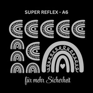 Könnte beinhalten: Schwarzer Hintergrund mit mehreren grauen Regenbogen-Designs. Der Text "SUPER REFLEX - A6" steht oben und "für mehr Sicherheit" unten. Die Regenbogen haben Herz- und Wirbeldetails.
