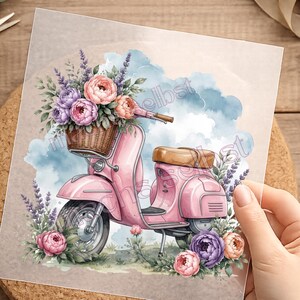 Könnte beinhalten: Ein quadratischer Druck mit einer Aquarellillustration eines rosafarbenen Rollers mit braunem Sitz und einem Weidenkorb voller violetter und rosafarbener Pfingstrosen und Lavendelzweige vor einem Hintergrund aus blauen und weißen Wolken.