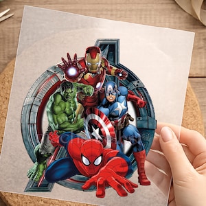 Könnte beinhalten: Ein kreisförmiger Grafikdruck mit Marvel-Superhelden, darunter Iron Man in rot-goldener Rüstung, der grüne Hulk, Captain America im blauen Anzug mit Schild und Spider-Man im rot-blauen Anzug, alles vor einem metallischen Rahmen.