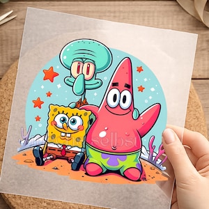 Könnte beinhalten: Ein transparenter Aufkleber mit einer farbenfrohen Illustration von SpongeBob Schwammkopf, Patrick Star und Thaddäus Tentakel vor einem hellblauen Hintergrund mit orangefarbenen Sternen. Der Text "Ich mache selbst" steht unten in heller Schrift.