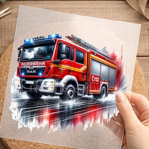 Könnte beinhalten: Ein rotes Feuerwehrauto mit dem Wort "FEUERWEHR" und der Marke "MAN" wird im Aquarellstil dargestellt. Das Fahrzeug hat blaue Lichter und die Nummer "112". Das Bild befindet sich auf einer transparenten Folie.