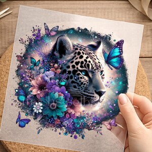 Könnte beinhalten: Ein quadratischer Aufkleber mit einem Leopardenkopf, umgeben von violetten und türkisfarbenen Blumen sowie leuchtend blauen Schmetterlingen. Das Design zeigt einen dunklen, sternenklaren kreisförmigen Hintergrund mit Lichteffekten und dem Text freshs selbst.
