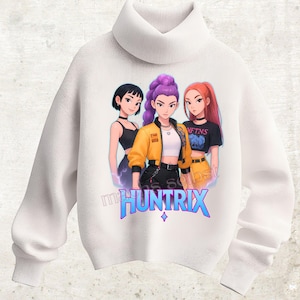 Könnte beinhalten: Weißer Rollkragenpullover mit einer farbenfrohen Grafik von drei Frauen im Anime-Stil. Die Frauen tragen stilvolle Outfits, und der Pullover hat den blauen Schriftzug "mHUNTRIX" und eine Raute.