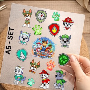 Könnte beinhalten: A5-SET-Bogen mit bunten Paw Patrol-Aufklebern. Die Aufkleber zeigen verschiedene Paw Patrol-Charaktere, Pfotenabdrücke und Schilde mit verschiedenen Symbolen. Die Aufkleber sind in verschiedenen Farben erhältlich, darunter Rot, Grün, Blau und Weiß.