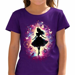 Könnte beinhalten: Ein lila T-Shirt mit einer Silhouette eines Mädchens in einem Kleid, umgeben von Schmetterlingen, Uhren und Teetassen. Das Design ist vor einem farbenfrohen, wirbelnden Hintergrund platziert. Das T-Shirt hat einen Rundhalsausschnitt.