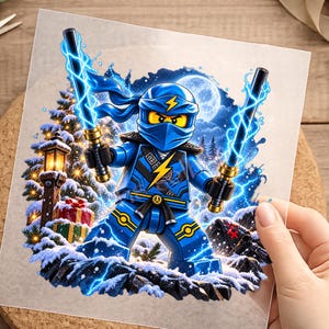 Könnte beinhalten: Eine blaue Ninja-Minifigur mit einem gelben Blitz-Emblem auf der Brust, die zwei leuchtende blaue Elektroschwerter hält. Die Szene zeigt eine verschneite Landschaft mit einer leuchtenden Laterne, verpackten Geschenken und einem Vollmond.