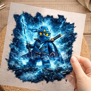 Könnte beinhalten: Ein quadratischer Grafikdruck mit einem blauen Ninja-Charakter in Maske und Rüstung, der ein leuchtendes blaues Schwert hält. Die Figur ist von dunkelblauen Blitzen und Energieeffekten umgeben. Der Text "machs sobst" ist im unteren Bereich sichtbar.