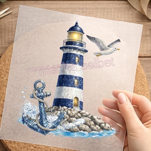 Könnte beinhalten: Ein maritimes Design mit einem blau-weiß gestreiften Leuchtturm, einem Anker und einer Möwe. Der Leuchtturm hat ein gelbes Licht. Der Text "machs-selbst" ist sichtbar. Das Design befindet sich auf einer transparenten Folie.