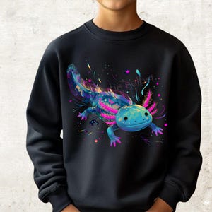 Könnte beinhalten: Schwarzes Sweatshirt mit einem farbenfrohen Axolotl-Design. Der Axolotl ist in Blau-, Lila- und Rosatönen dargestellt, mit einem Sternenhintergrund und dem Text "his agility". Ein lebendiges und auffälliges Design.