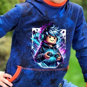 Könnte beinhalten: Blauer Kapuzenpullover mit einem Grafik eines Gamers mit Kopfhörern und Controller. Der Pullover hat ein blaues und schwarzes Muster mit orangefarbenen Verzierungen an Kapuze und Tasche.