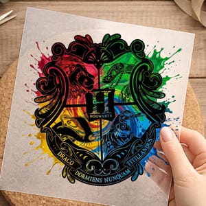 Könnte beinhalten: Ein klarer, quadratischer Aufkleber mit dem Hogwarts-Wappen. Das Wappen ist in vier Abschnitte unterteilt, jeder mit einem anderen Tier und einer anderen Farbe. Die Wörter "Hogwarts", "Draco", "Dormiens Nunquam" und "Titillandus" sind ebenfalls sichtbar. Aquarell-Effekt.