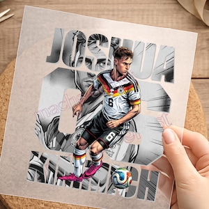 Könnte beinhalten: Ein Grafikdruck auf einer transparenten Folie zeigt einen Fußballspieler in einem weiß-schwarz-gelben Trikot mit der Nummer 6, schwarzen Shorts und pinken Fußballschuhen. Der Name JOSHUA steht in großen Buchstaben über einem Fußball.
