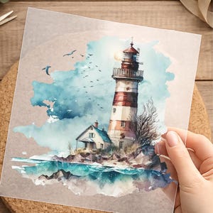 Könnte beinhalten: Eine Illustration im Aquarellstil auf einem quadratischen Blatt mit einem rot-weiß gestreiften Leuchtturm und einem kleinen Haus an einer felsigen Küste. Die Szene zeigt blaue Meereswellen, eine blasse Sonne und Vögel am blauen Himmel.