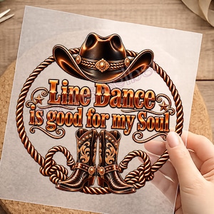 Könnte beinhalten: Ein kreisförmiges Grafikdesign mit einem braunen Cowboyhut oben und einem Paar brauner Cowboystiefel unten, alles umschlossen von einer Seilbordüre. Der Text "Line Dance is good for my Soul" ist in der Mitte in einer metallischen Schrift.