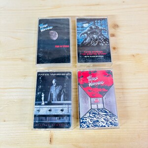 May include: Four vintage Fates Warning cassette tapes. The tapes feature album art with a night sky, a horned figure, a man in a room, and a red and white design with the words "NO EXIT".