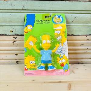 May include: A bendable Bart Simpson action figure in its original packaging. The figure is yellow with a blue shirt, shorts, and shoes. The packaging is green and features other Simpsons characters and the text "BENDABLE ACTION FIGURE".