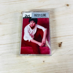 Op de afbeelding: Een Patsy Cline cassettebandje uit de 20th Century Masters collectie. De hoes toont een foto van Patsy Cline in een wit overhemd en een rode broek. De cassette is transparant en de achtergrond is licht hout.