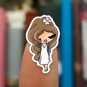 May include: A sticker of a cartoon girl with brown hair, wearing a white dress and a blue cardigan. She has a pink flower in her hair and is smiling.
