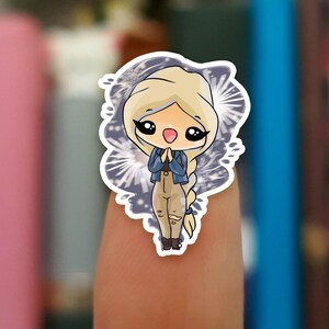 Peut inclure: Un autocollant représentant une fille de dessin animé aux cheveux blonds, portant une veste en jean bleue et un pantalon marron. Elle se tient devant un fond blanc avec un motif de feu d'artifice bleu et blanc.