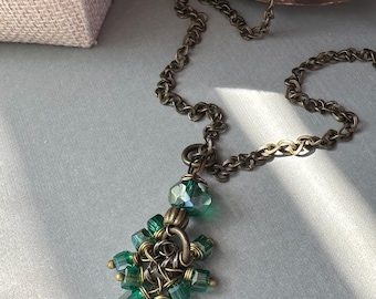 Colgante de cuentas de vidrio verde esmeralda con detalles de latón.