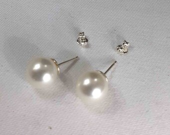 Elegant stud earrings mounted with white freshwater pearls .