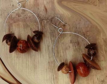 Appealing solid silver hoop earrings adorned with wooden beads and seeds .