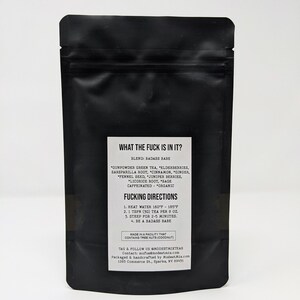May include: Black tea bag with white text that reads "WHAT THE FUCK IS IN IT?" and "FUCKING DIRECTIONS". The tea blend includes gunpowder green tea, elderberries, and other organic ingredients. The bag is sealed and stands upright.