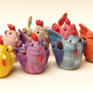 以下が含まれることがあります： 異なるパターンと色で、8羽のカラフルな布製の鶏のセット。鶏はすべて、翼に小さなひよこを抱えています。