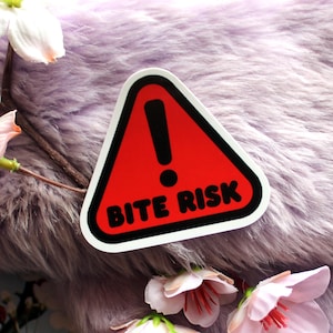 May include: A red triangle warning sign with a black exclamation point and the text "BITE RISK" in black.