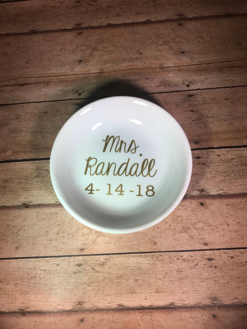 May include: White ceramic ring dish with gold lettering that reads "Mrs. Randall 4-14-18".