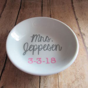 May include: White ceramic ring dish with the text "Mrs. Jeppesen" in gray and "3-3-18" in pink.