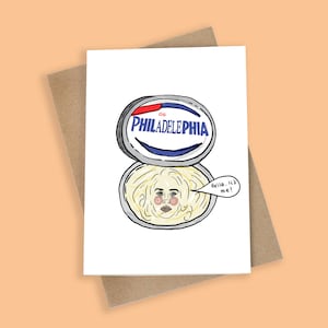 May include: A humorous greeting card showing a Philadelphia cream cheese container with a face inside. The card says "Hello, It's me!" The card is on a brown envelope. The illustration is in a cartoon style.