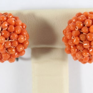 May include: A pair of coral earrings, each earring is a cluster of small, round, orange coral beads.
