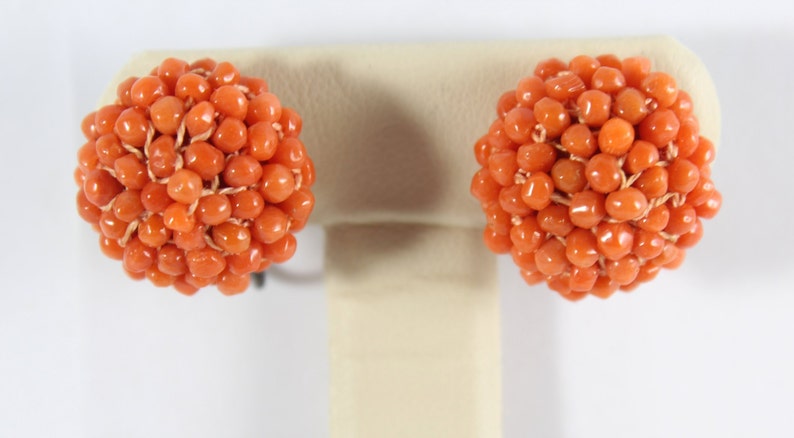 May include: A pair of coral earrings, each earring is a cluster of small, round, orange coral beads.