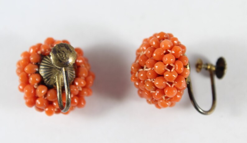 May include: A pair of orange coral bead earrings with gold-tone clip-on backs.