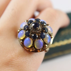 May include: A gold ring with a cluster of opals and sapphires. The opals are iridescent and the sapphires are dark blue.