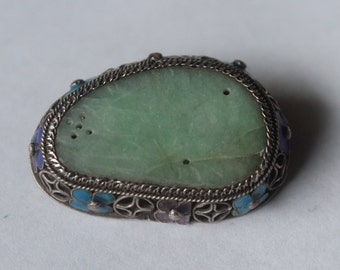 May include: A jade pendant with a silver filigree frame and blue and purple enamel flowers.