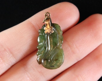 May include: A green jade pendant carved in the shape of a leaf with a gold flower accent. The pendant is attached to a gold bail.