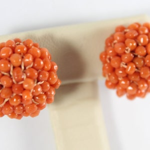 May include: A pair of orange coral earrings, each earring is a sphere made of small coral beads.