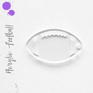 May include: Clear acrylic football keychain. The keychain is shaped like a football with a stitched seam detail.