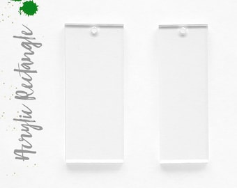 May include: Two clear acrylic rectangle blanks with a hole at the top for jewelry making or crafting. The text "Acrylic Rectangle" is written in gray script on the left side of the image, with green paint splatters.