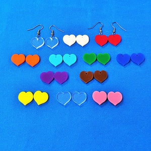 May include: Assortment of colorful heart-shaped earrings with silver hooks. The earrings are made of acrylic and come in a variety of colors, including red, blue, green, yellow, purple, and clear.