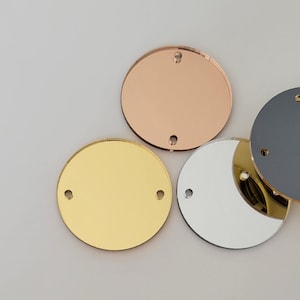 May include: Three round, mirrored acrylic discs in gold, silver, and rose gold. Each disc has two small holes near the edge.