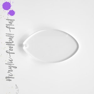 May include: Clear acrylic football-shaped blank for crafting. The blank is oval-shaped and has a hole at the top for hanging.