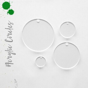 May include: Four clear acrylic circles of varying sizes with a small hole at the top of each circle. The circles are arranged on a white surface.