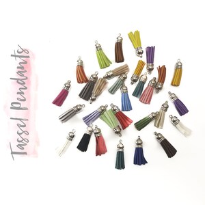 May include: A collection of colorful tassel pendants with silver-colored caps. The tassels come in various colors, including pink, green, blue, and brown. The words "Tassel Pendants" are written in a script font on the left side of the image.
