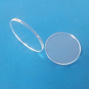 May include: Two clear round acrylic discs on a blue background.