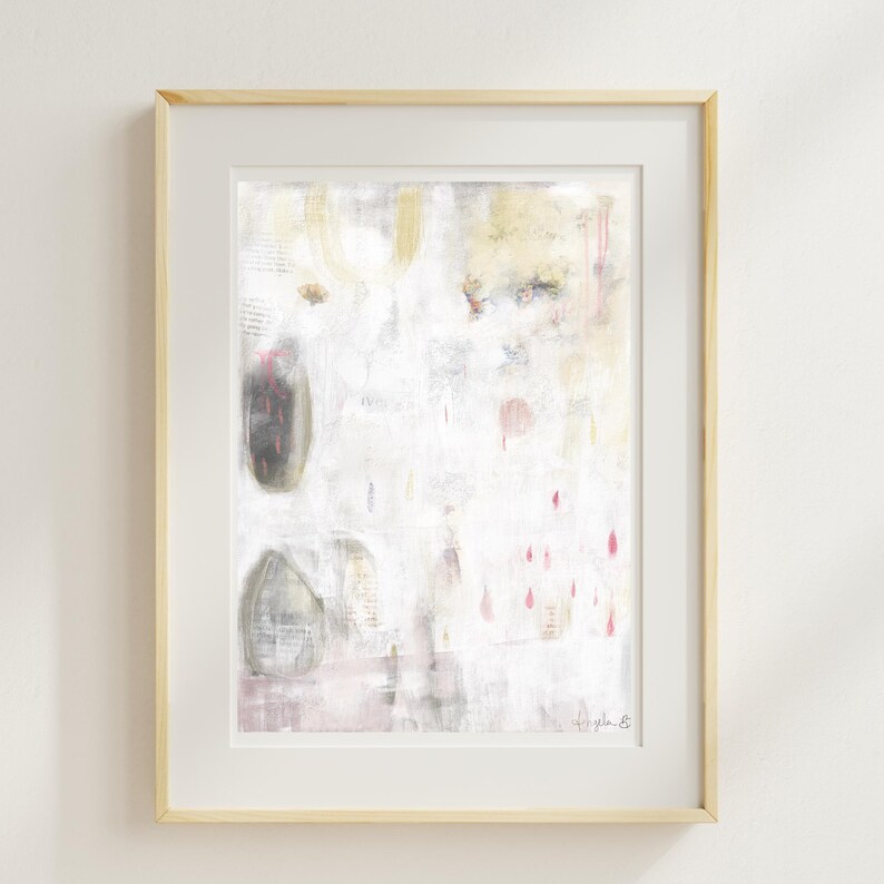 May include: An abstract painting in a light wood frame featuring a white background with soft gray, yellow, and pink accents. The composition includes layered textures, faint vertical lines, and small droplet shapes in pink, with a signature in the bottom right.